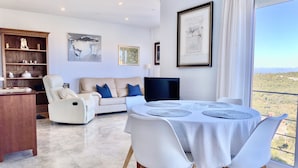 A spacious living room with a sofa, a dining table with chairs, and a large window offering a view of the countryside. - House with spectacular sea views in the historic centre of Begur (Begur)
