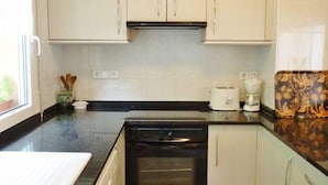 A compact kitchen with white cabinets, a black oven, and a coffee maker on the countertop. - House with spectacular sea views in the historic centre of Begur (Begur)