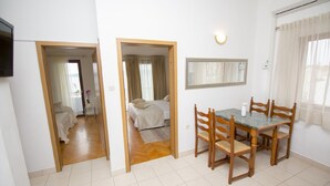 Ein Zimmer mit Esstisch und Stühlen, einem Bett mit Kopfteil, einem Spiegel an der Wand und einem an der Wand befestigten Fernseher.