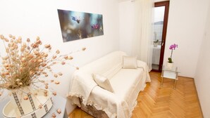 Ein Schlafzimmer mit einem Bett, einer Vase mit getrockneten Blumen, einem Bild an der Wand und einer Tür, die auf einen Balkon führt.
