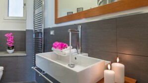 Een moderne badkamer met een wit wastafelmeubel, een handdoekhouder en een spiegel boven het wastafelmeubel.