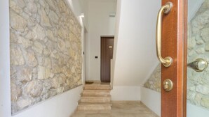 A hallway with a stone wall, a wooden door with a brass handle, and a staircase leading to a room. - HELMI34 - A flat with all comforts in the centre of Cagliari (Cagliari)