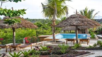 Un espace aménagé au bord de la piscine, avec des parasols en chaume, des chaises longues et une piscine.