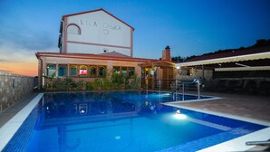 Ein Schwimmbecken mit einem Gebäude im Hintergrund, auf dem "Villa Caska" steht.