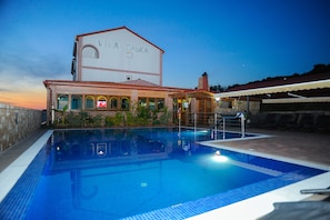 Ein Schwimmbecken mit einem Gebäude im Hintergrund, auf dem "Villa Caska" steht.