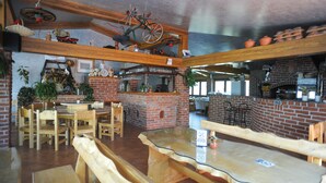 Ein Restaurant mit Holztischen, Backsteinwänden und einem Backofen.