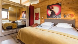 A bedroom with a large mirror, a bed with white linens, a wooden headboard, and a poster on the wall. - StroEnzo - Cozy straw-bale holiday home - Tongeren / Maastricht - 5pers   (Riemst)