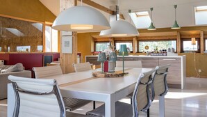 A modern kitchen with wooden beams, a dining area with white table and chairs, and pendant lighting. - StroEnzo - Cozy straw-bale holiday home - Tongeren / Maastricht - 5pers   (Riemst)
