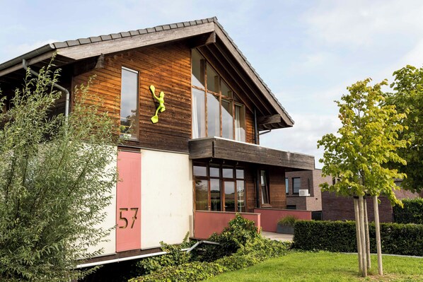 A modern building with a wooden facade, large windows, and a number '57' on the side. - StroEnzo - Cozy straw-bale holiday home - Tongeren / Maastricht - 5pers (Riemst)