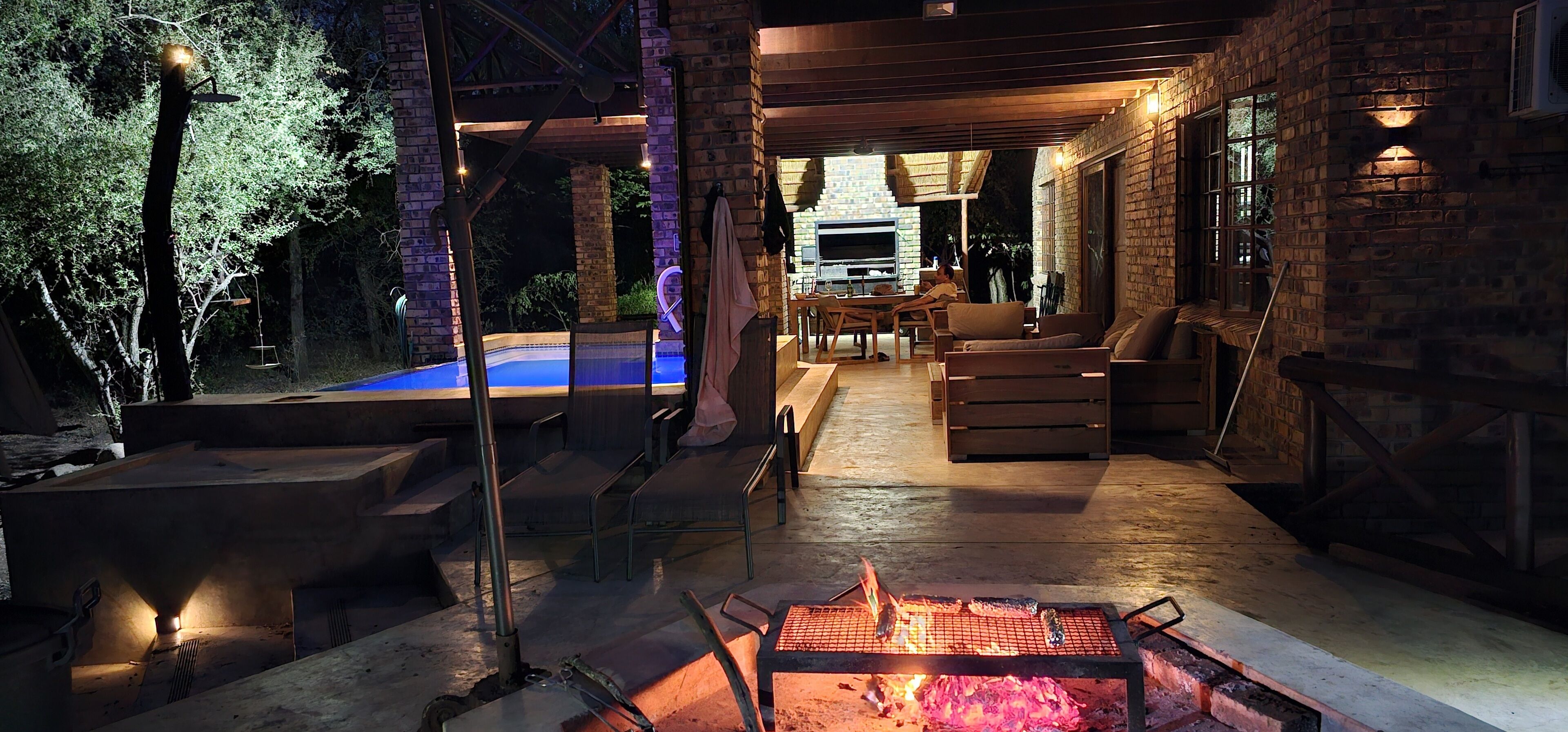 Un espacio al aire libre con un pozo de fuego, asientos y una piscina.