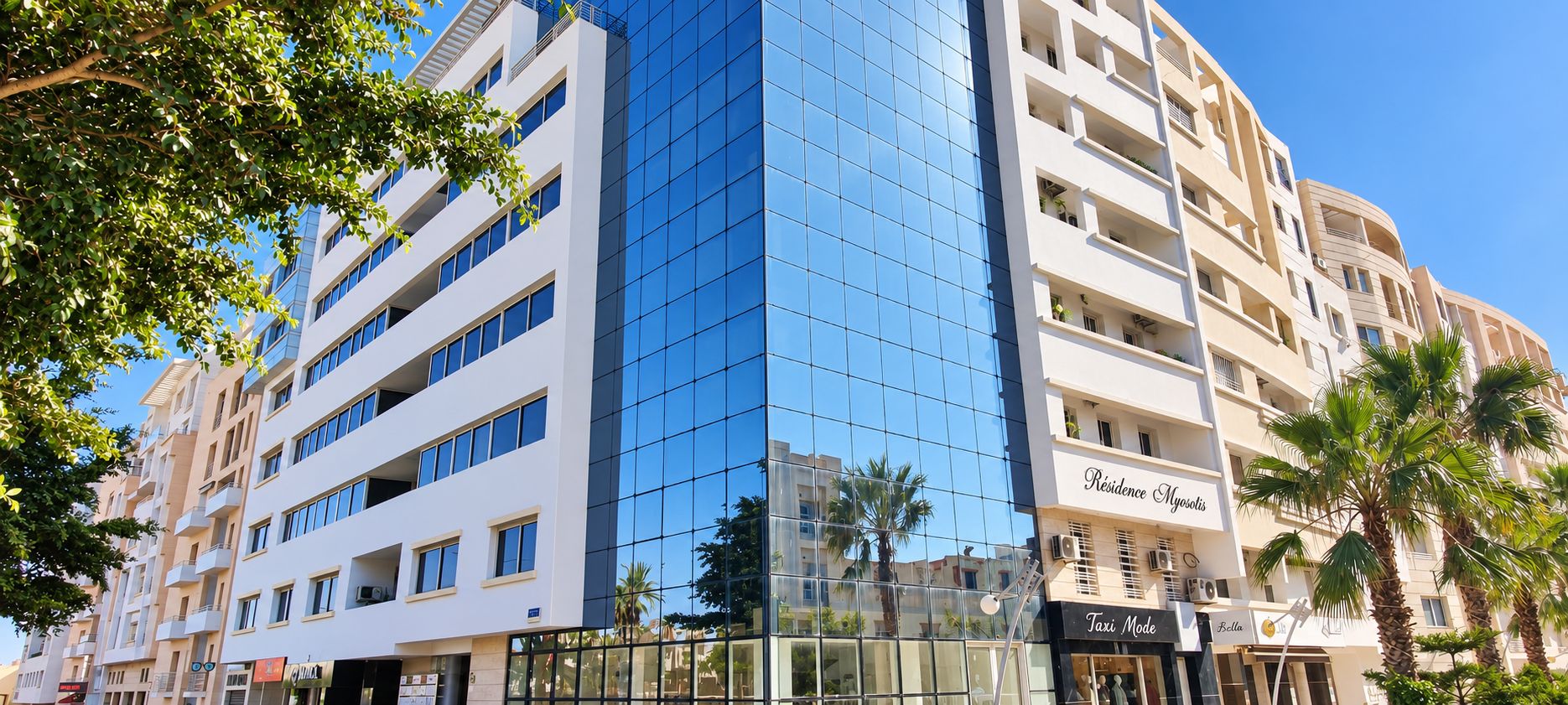 A multi-story building with a glass facade, balconies, and a sign for 'Residence Mysotys.'