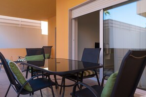 A glass-top table with four chairs, each with a green cushion.