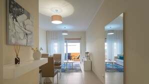 A modern hotel lobby with a seating area, a large painting, and a view to the outside.