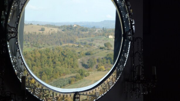 Janela redonda com vista para uma paisagem montanhosa.
