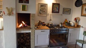 Uma cozinha com lareira, fogão, forno e diversos utensílios.