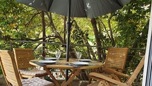 A round wooden table with four chairs, each with cushioned seats, under a large umbrella. - Apartment Keti spacious apartment in the center of Korcula town with sea view (Korčula, Dubrovačko-neretvanska županija)