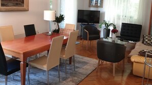 A modern living room with a dining area, a TV, and a ceiling fan. - Apartment Keti spacious apartment in the center of Korcula town with sea view (Korčula, Dubrovačko-neretvanska županija)