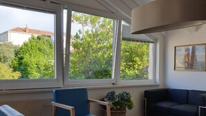 A modern living room with large windows, a round white table, blue chairs, and a dark sofa. - Apartment Keti spacious apartment in the center of Korcula town with sea view (Korčula, Dubrovačko-neretvanska županija)