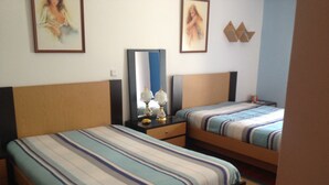 Une chambre d’hôtel avec deux lits, chacun doté de draps à rayures, une table de chevet avec une lampe et des tableaux encadrés accrochés au mur.