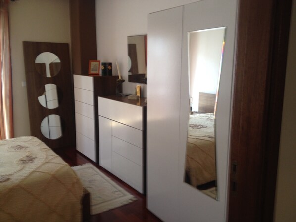 A bedroom with a bed, a wardrobe, a mirror, and a door with circular cutouts. - T2 in Nazaré 100m from the beach (Nazaré)