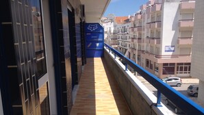 Un couloir au sol carrelé, un panneau bleu orné de logos, et une vue sur des immeubles et des voitures garées.