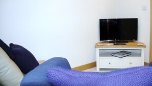 A bedroom with a bed, a nightstand with a TV, and a door. - The Starting Gate - luxury studio apartment, rural location, 1m from Bruton (Bruton)