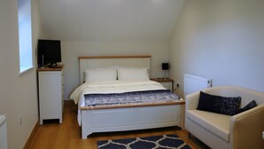 A bedroom with a bed, bedside table, lamp, and a sofa. - The Starting Gate - luxury studio apartment, rural location, 1m from Bruton (Bruton)
