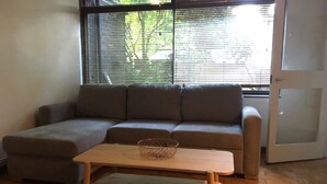 Una sala de estar con un sofá seccional, una mesa de centro de madera y un ventanal que da al exterior.