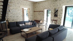 A living room with stone walls, a sofa set, a coffee table, and a wicker basket labeled "LON".