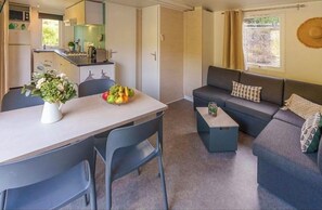 Ein kompakter Wohnbereich mit Küchenzeile, einem Essbereich mit Tisch und Stühlen, einer Couch und einem kleinen Couchtisch.