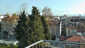 Stadsbeeld met woongebouwen, een grote boom en een heldere lucht.