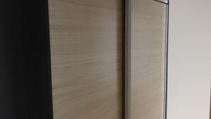 Een kamer met een schuifdeur, houten vloer en een effen witte muur.