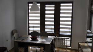 Een eetgedeelte met een tafel, stoelen, een schaal, een laptop en een hanglamp.