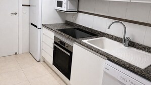 A kitchen with white cabinets, a microwave, a stove, a dishwasher, and a sink. - New apartment with stunning views (Calpe)