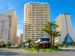 A modern hotel with a distinctive pyramid-shaped building, a large central tower, and a boat sculpture in the foreground. - New apartment with stunning views (Calpe)