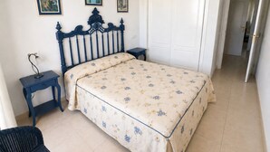 A bedroom with a bed, a nightstand, a lamp, a chair, and a door. - New apartment with stunning views (Calpe)