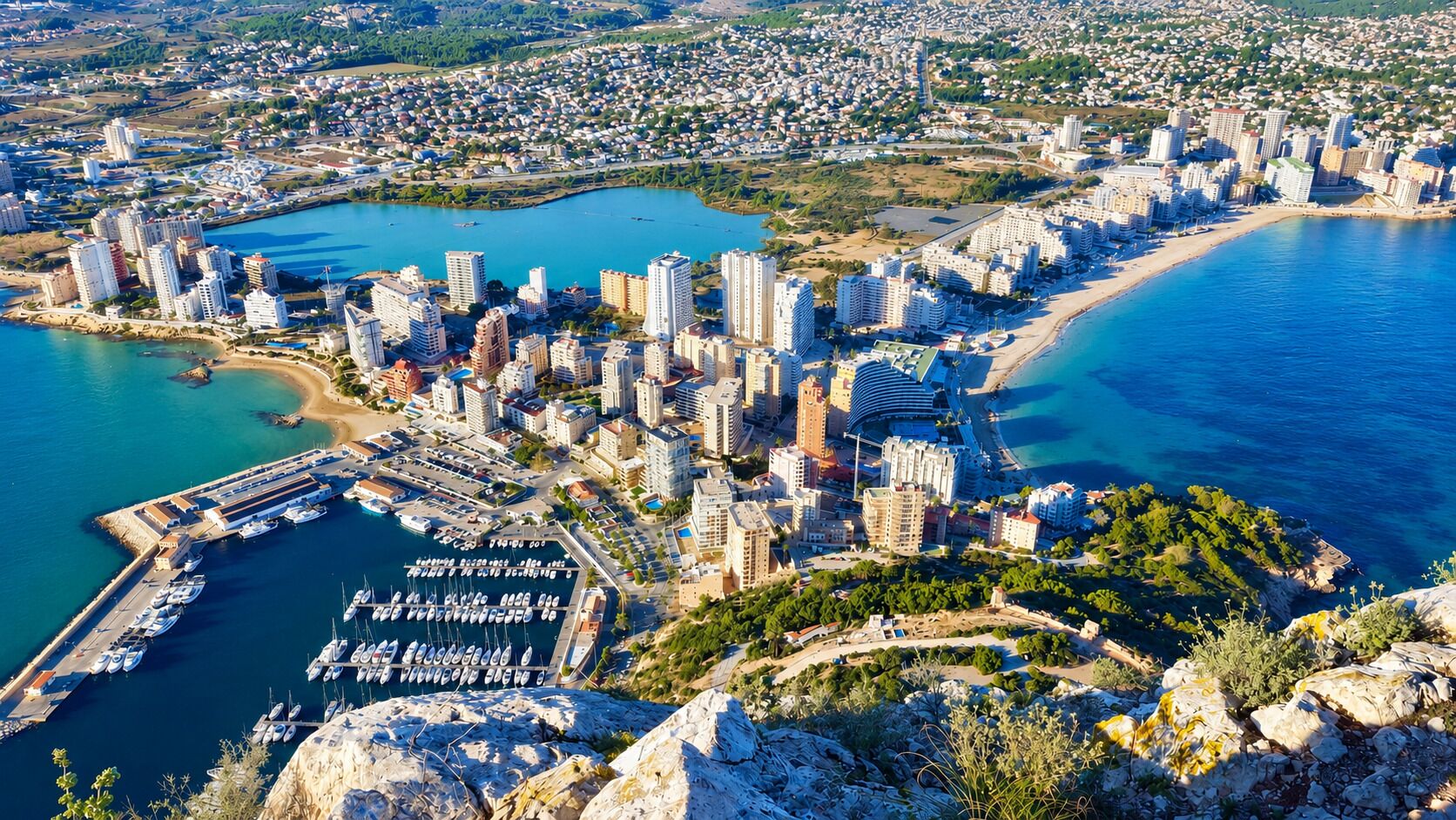 A coastal cityscape with high-rise buildings, a marina, and a beach.