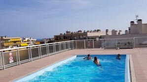 A rectangular pool with clear blue water, surrounded by a tiled deck and a metal railing. - Apartment T2 air-conditioned, Wifi Fibre, Garage, 4 people (Le Cannet)