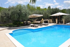 A swimming pool with lounge chairs and umbrellas, surrounded by greenery. - Hillside villa with pool (Messina)
