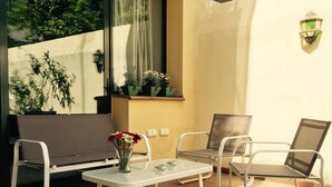 Un patio con una mesa blanca, dos sillas y un florero con flores.