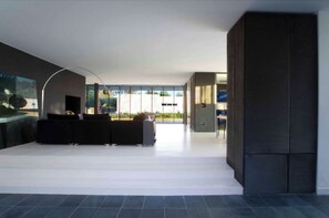Relax in this open-plan living space with a black sectional sofa, abstract art, and a flat-screen TV.