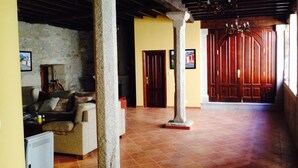 A spacious living area with a stone wall, a wooden door, and a tiled floor. - Bed Century XII - Pontevedra (Ribeira Sacra) (Fornas - Pontevedra)