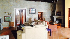 A cozy living room with stone walls, a fireplace, and a comfortable seating area. - Bed Century XII - Pontevedra (Ribeira Sacra) (Fornas - Pontevedra)