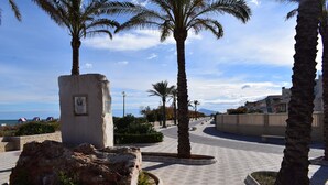 A paved walkway with palm trees, a stone monument, and a view of the sea. - Anacasa Illa de Mallorca Pau Pi AP6320 (Oliva)