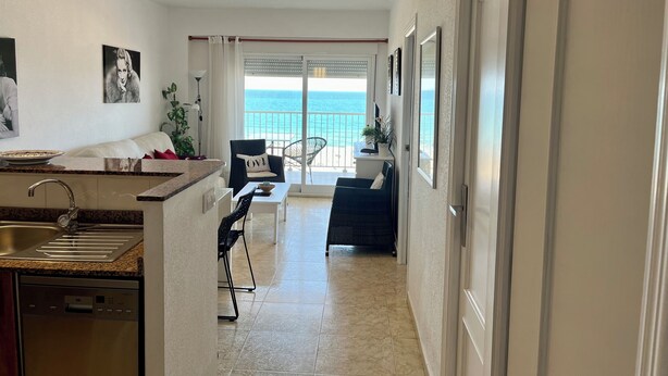 A modern kitchen with a built-in dishwasher, a dining area with a view of the ocean, and a balcony with a railing. - Beautiful apartment on the beachfront (PLAYA-GRAU DE GANDÍA)