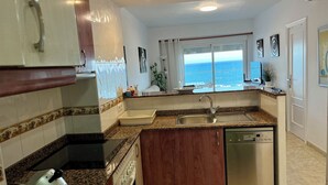 A modern kitchen with granite countertops, stainless steel appliances, and a view of the ocean. - Beautiful apartment on the beachfront (PLAYA-GRAU DE GANDÍA)
