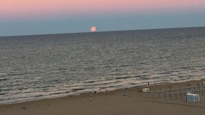 A beach with a calm sea, a visible moon, and a few people walking along the shore. - Beautiful apartment on the beachfront (PLAYA-GRAU DE GANDÍA)