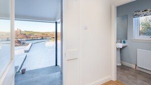 A room with a view of a snowy landscape, a window with a curtain, a white sink, and a radiator. - Balass Lodge near St. Andrews (Cupar)