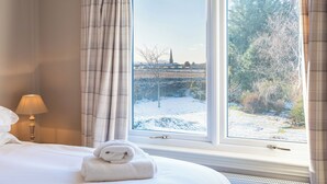 A hotel room with a large window, a bed, a lamp, and a rolled towel on the bed. - Balass Lodge near St. Andrews (Cupar)