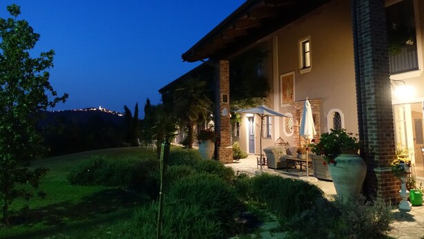 A two-story house with a patio area, a brick chimney, and a view of a hill. - Cascina Arcangelo Raffaele, Apartment Gabriele (VERDUNO)